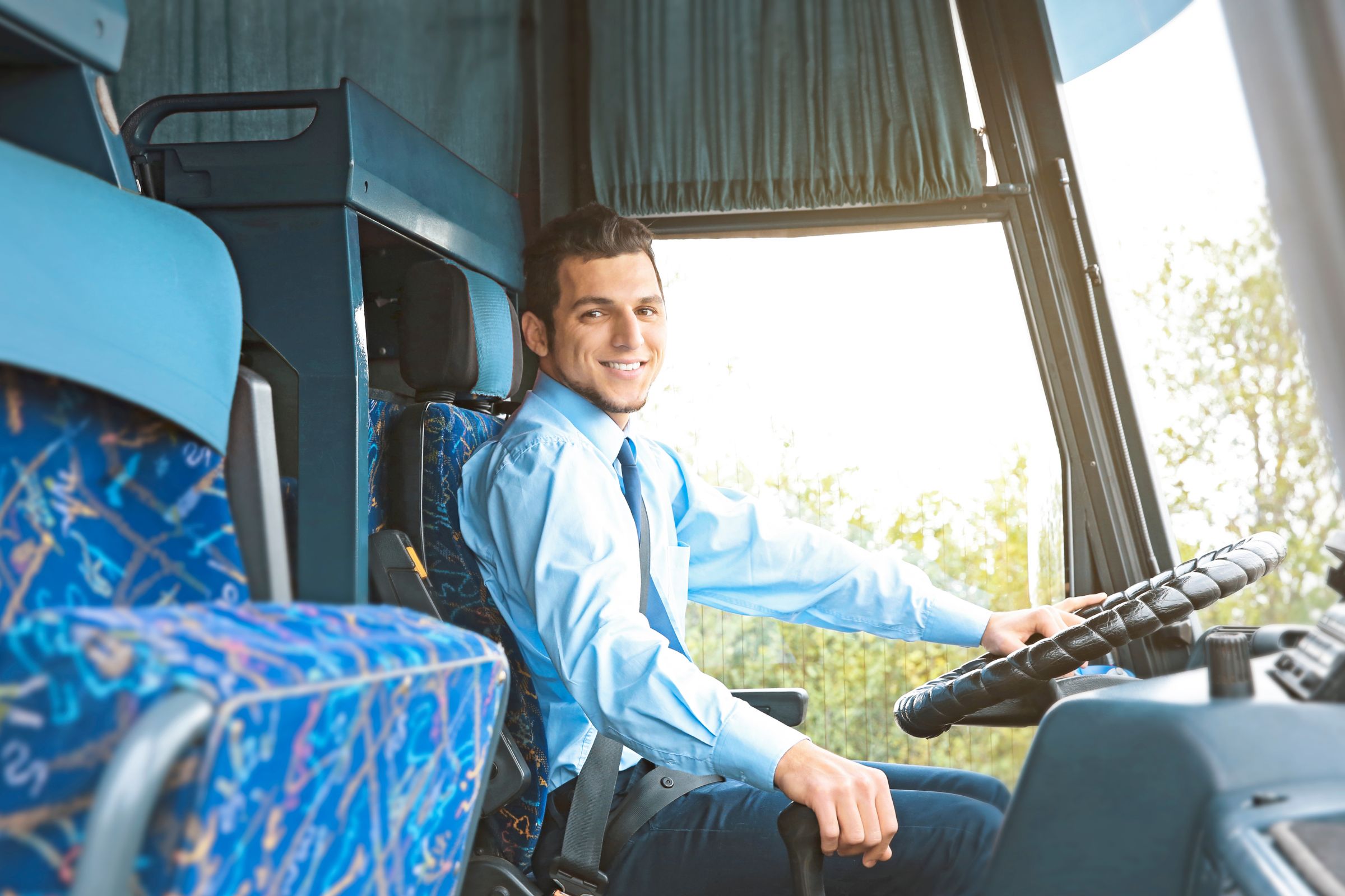 Man sitting in the driver's seat of a bus, smiling.